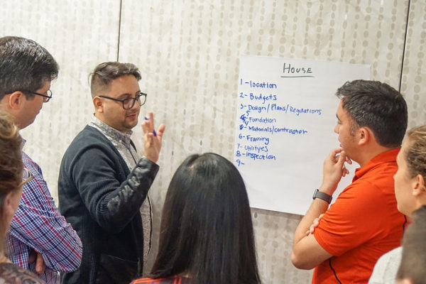academy participants listen as a fellow participant talks while looking at a hand-drawn notes.