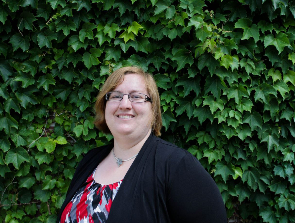 Jen Bethmann poses in front of a leafy background