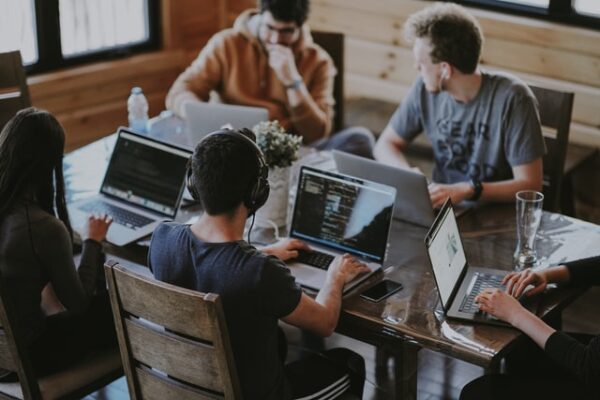 Young people sit around a table on computers