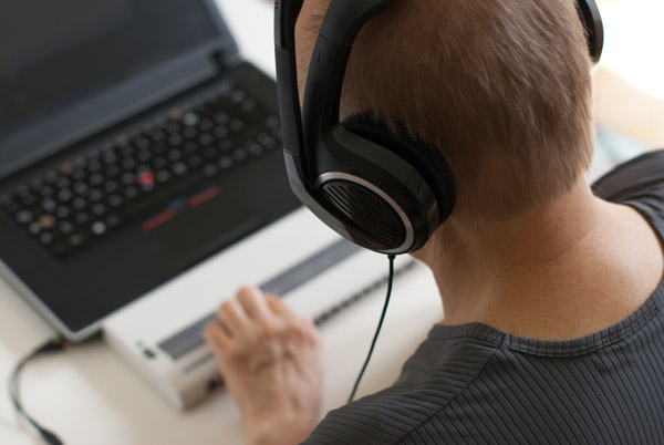 A person uses a laptop with headphones.
